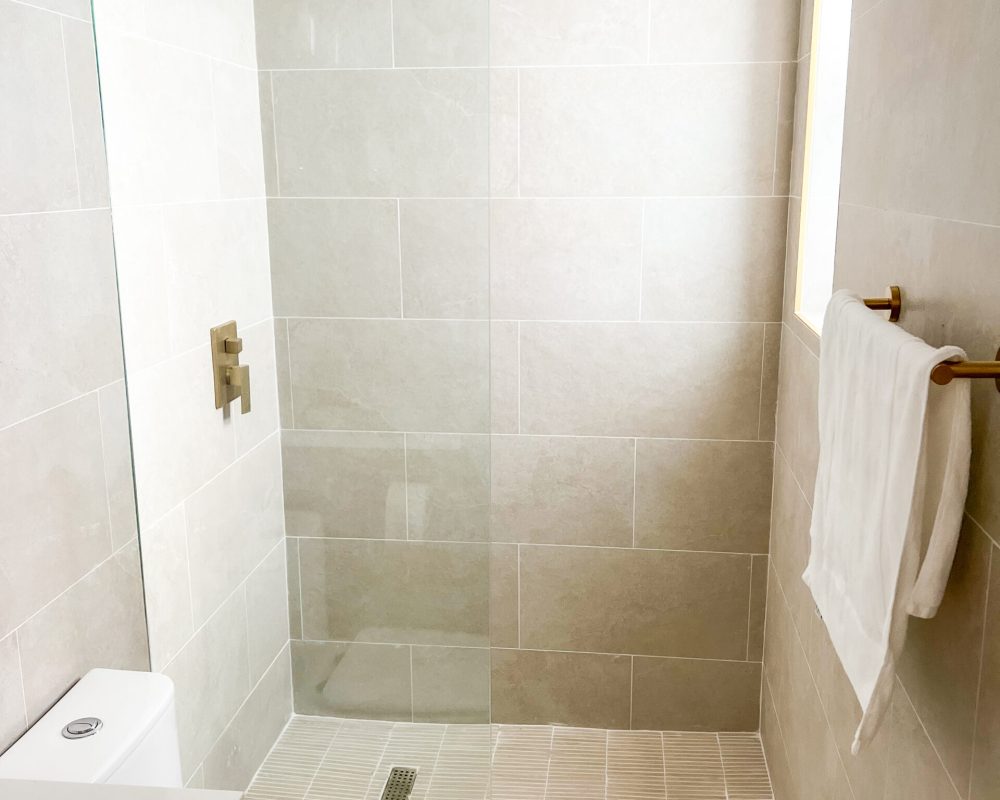 Deluxe and Standard Room bathroom at Tiana Beach Inn with tiled shower and vanity