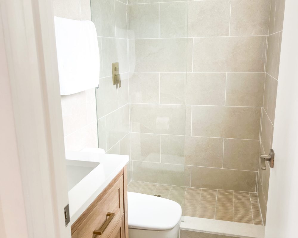 Contemporary bathroom with glass shower in boutique hotel room at Tiana Beach Inn