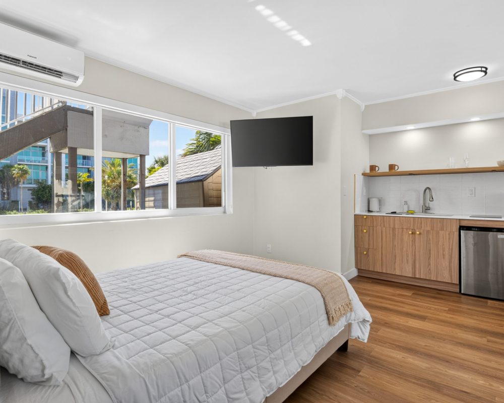 Queen bed and kitchenette in the Deluxe Quadruple Room at Tiana Beach Inn