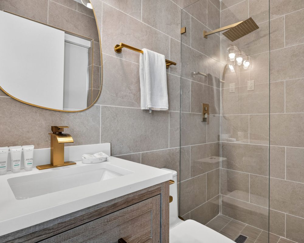 Modern bathroom with walk-in shower in the Deluxe Quadruple Room at Tiana Beach Inn