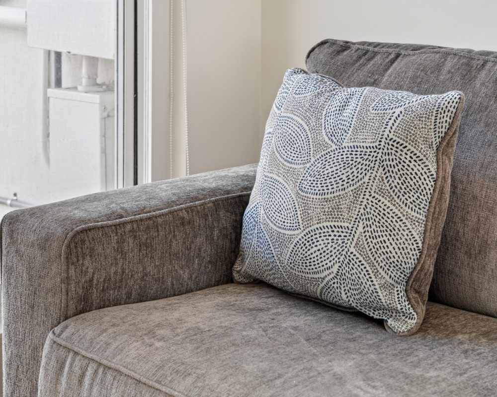 Comfortable sofa and decorative cushion in the Deluxe Quadruple Room