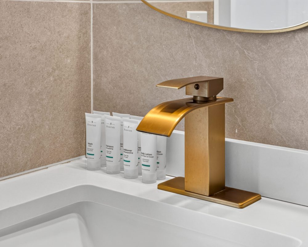 Bathroom amenities and modern gold faucet in the Deluxe Quadruple Room