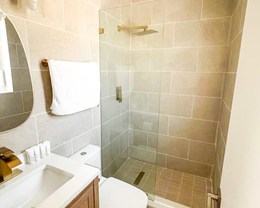 Modern hotel bathroom with glass shower in Deluxe and Standard Rooms at Tiana Beach Inn